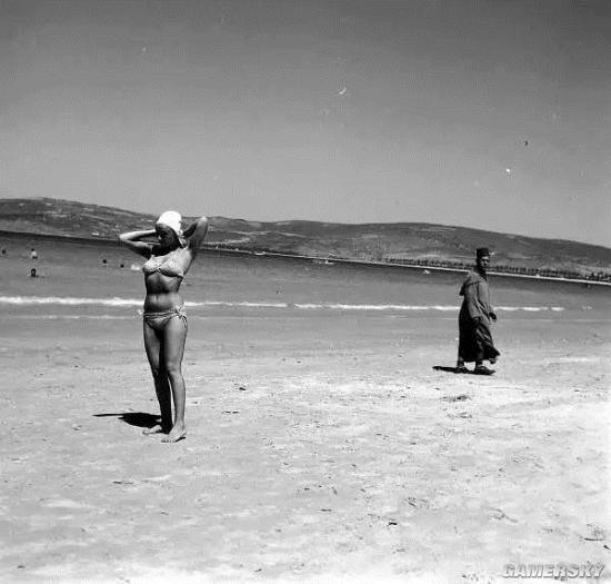 1957年,一名男子在摩洛哥的海滩上观察一个穿比基尼的女子